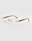 As part of the Rose Garden collection, Claremont rimless eyeglasses from For Art's Sake® feature rectangular lenses with gold temple detailing and clear surfaces. The brown arms showcase a tortoiseshell pattern, and the brand name appears on the lens against a light gray background.