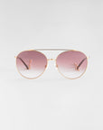 A pair of stylish aviator sunglasses named Yoyo by For Art's Sake® with 18k gold-plated metal frames and gradient pink-tinted lenses is centered against a plain, light gray background. The Yoyo sunglasses feature thin arms and adjustable nose pads for comfort.