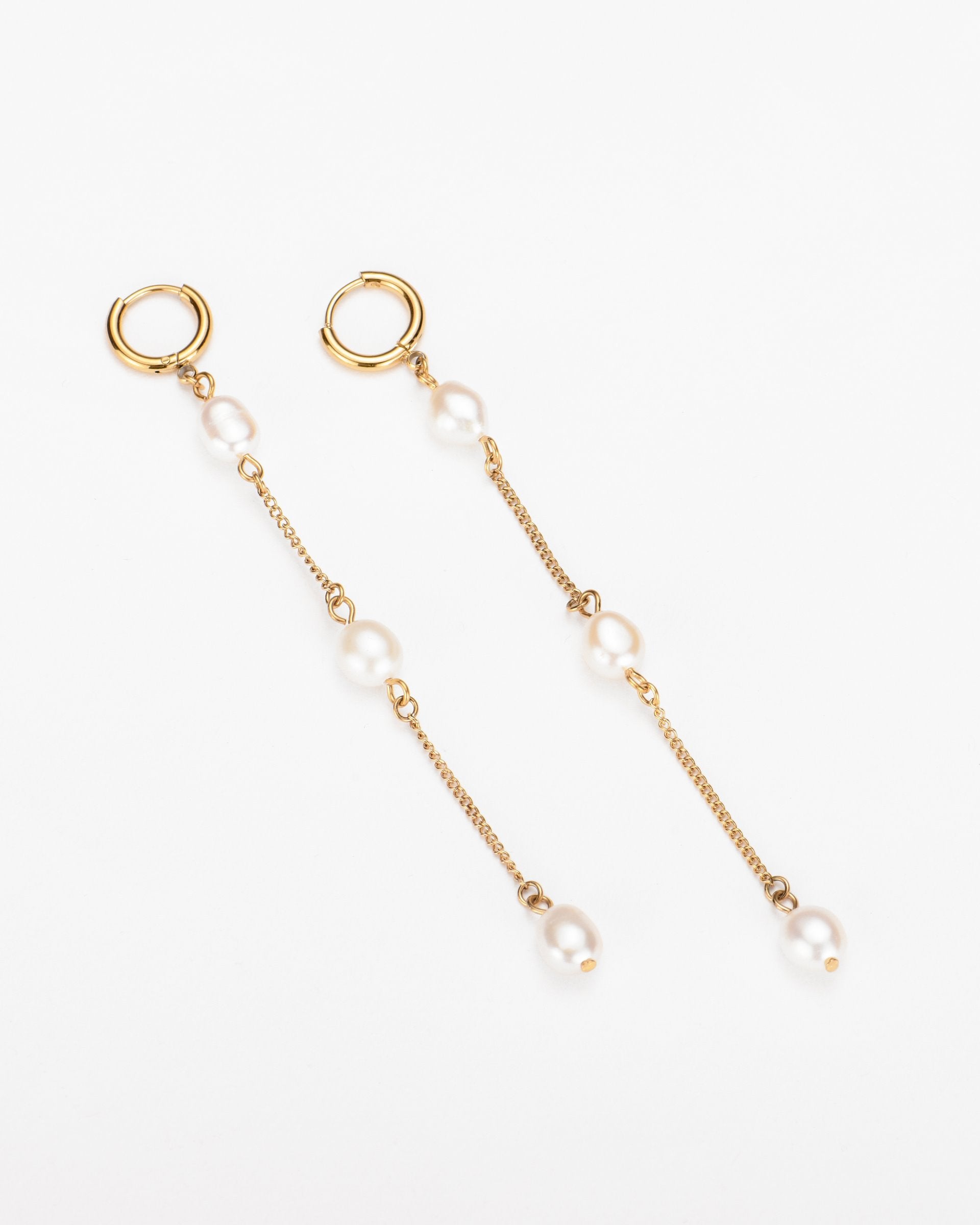 A pair of elegant Yoyo earrings by For Art&#39;s Sake® featuring gold hoops with 18k gold plating, attached to delicate chains adorned with three evenly spaced freshwater pearls. The earrings are laid side by side against a plain white background.