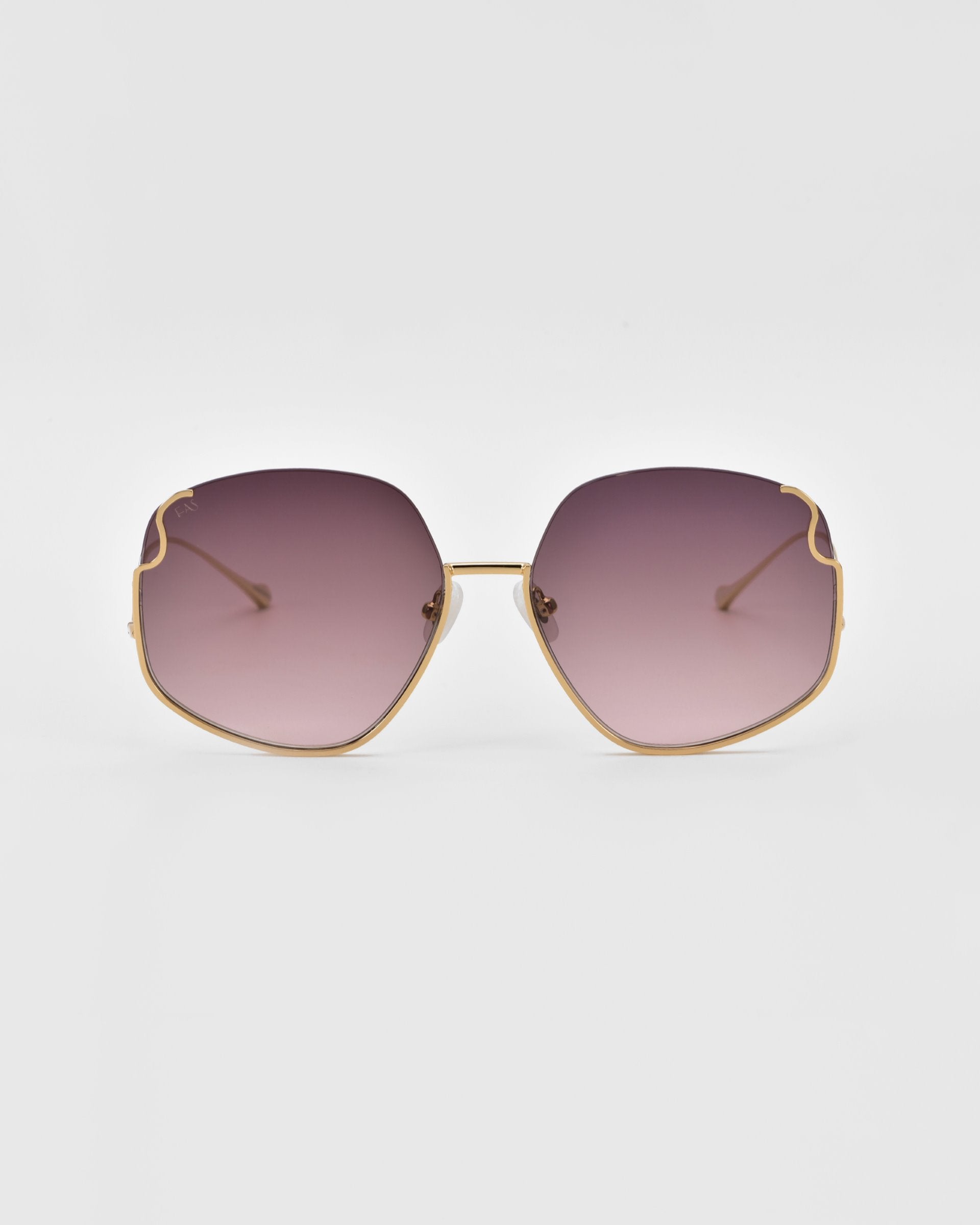 A pair of luxurious Drape sunglasses by For Art&#39;s Sake® with large, hexagonal lenses featuring a gradient tint from dark purple at the top to lighter purple towards the center. The gold-colored frame showcases intricate metal detailing and thin, delicate arms.