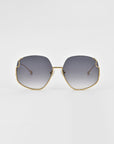 A pair of For Art's Sake® Drape sunglasses with large, hexagonal lenses featuring a gradient tint from dark grey to light grey. The sunglasses have a thin, gold metal frame with intricate metal detailing and delicate gold temples. The background is a plain, soft white.