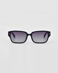 A pair of For Art's Sake® Zenith sunglasses with black rectangular frames made from handcrafted acetate stand against a plain, light grey background. Enhanced with sleek, slightly curved lines and chunky chain detailing, they exude a modern, stylish look.