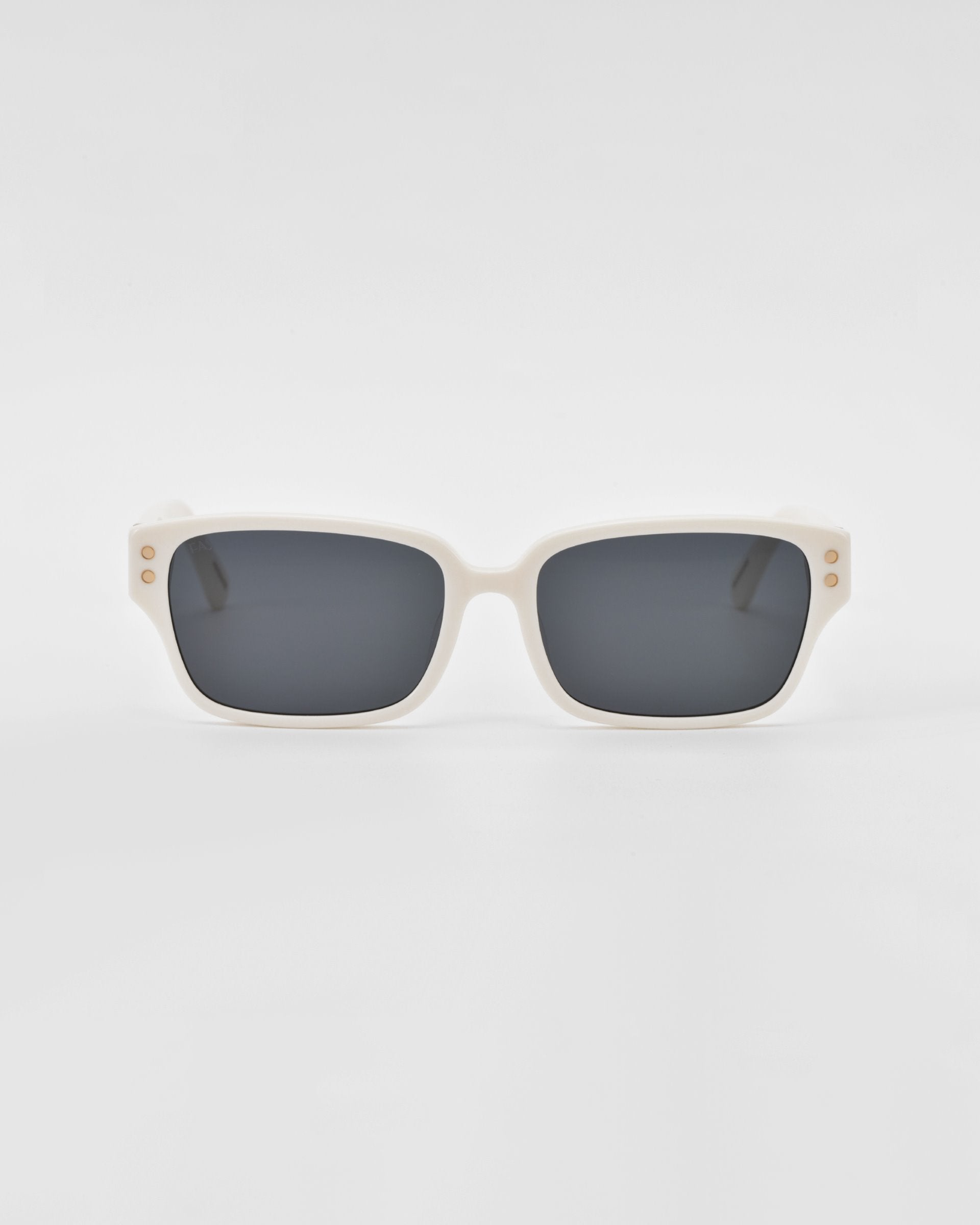 A pair of For Art&#39;s Sake® Zenith sunglasses with rectangular, white handcrafted acetate frames and dark lenses. The frames feature small, gold circular accents near the hinges on both sides. The background is plain and white, emphasizing the stylish design.