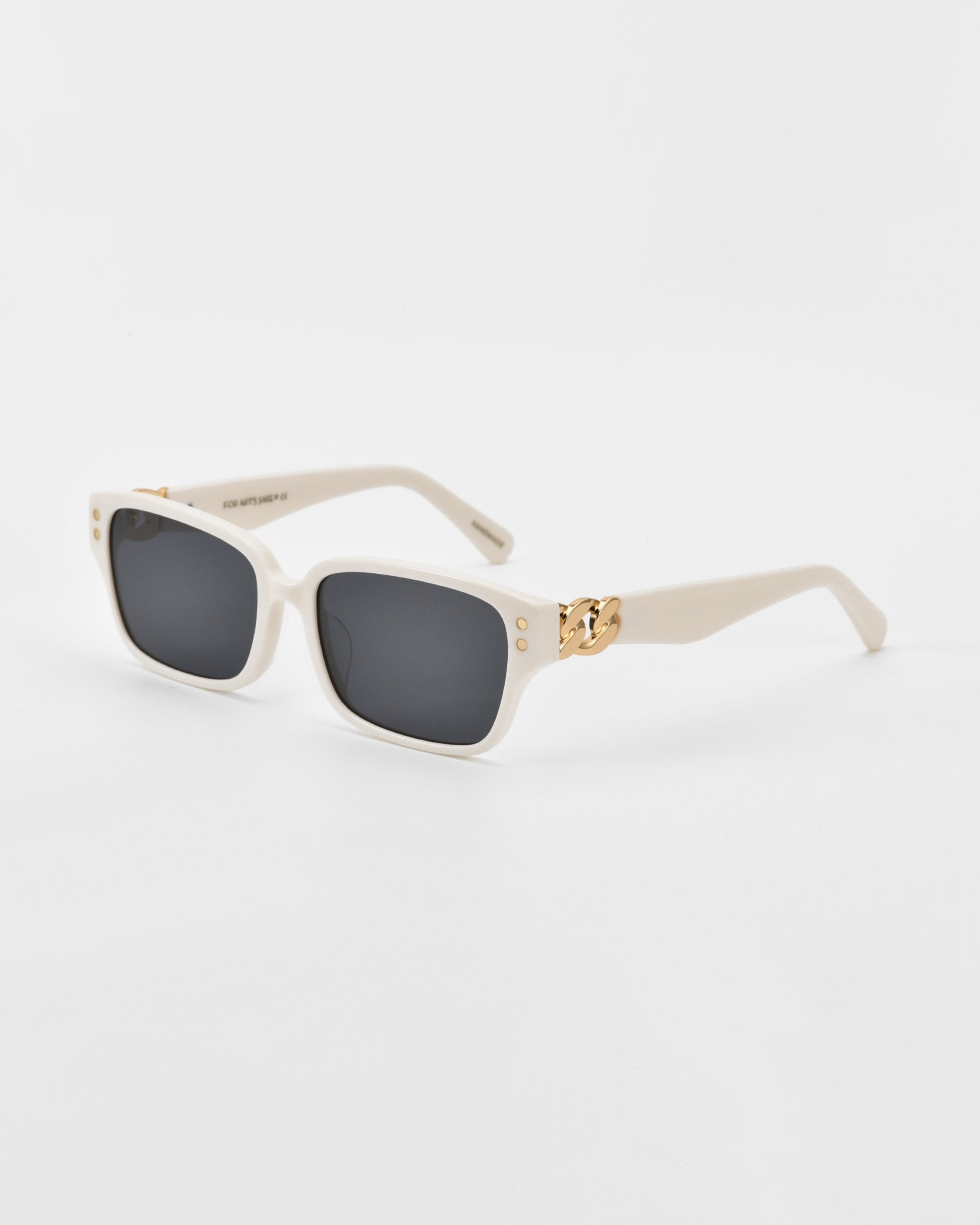 Image of a stylish pair of white For Art&#39;s Sake® Zenith sunglasses with dark lenses. The frame, handcrafted from acetate, features gold decorative elements at the hinges, adding a touch of elegance to the design. The background is plain white.