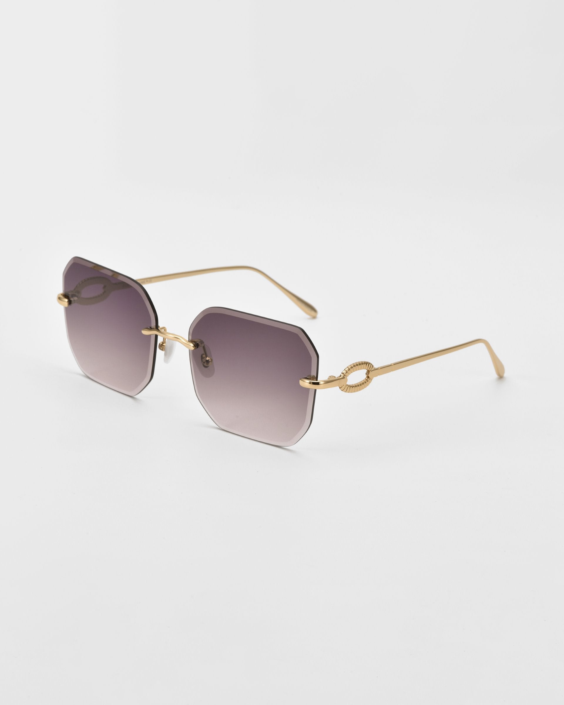 A pair of stylish For Art&#39;s Sake® Aria sunglasses with thin, gold metal frames and gradient dark, diamond-cut lenses. The temples have a distinctive gold knot detail near the lenses and extend into sleek, straight arms with jade-stone nose pads. The background is plain and white.