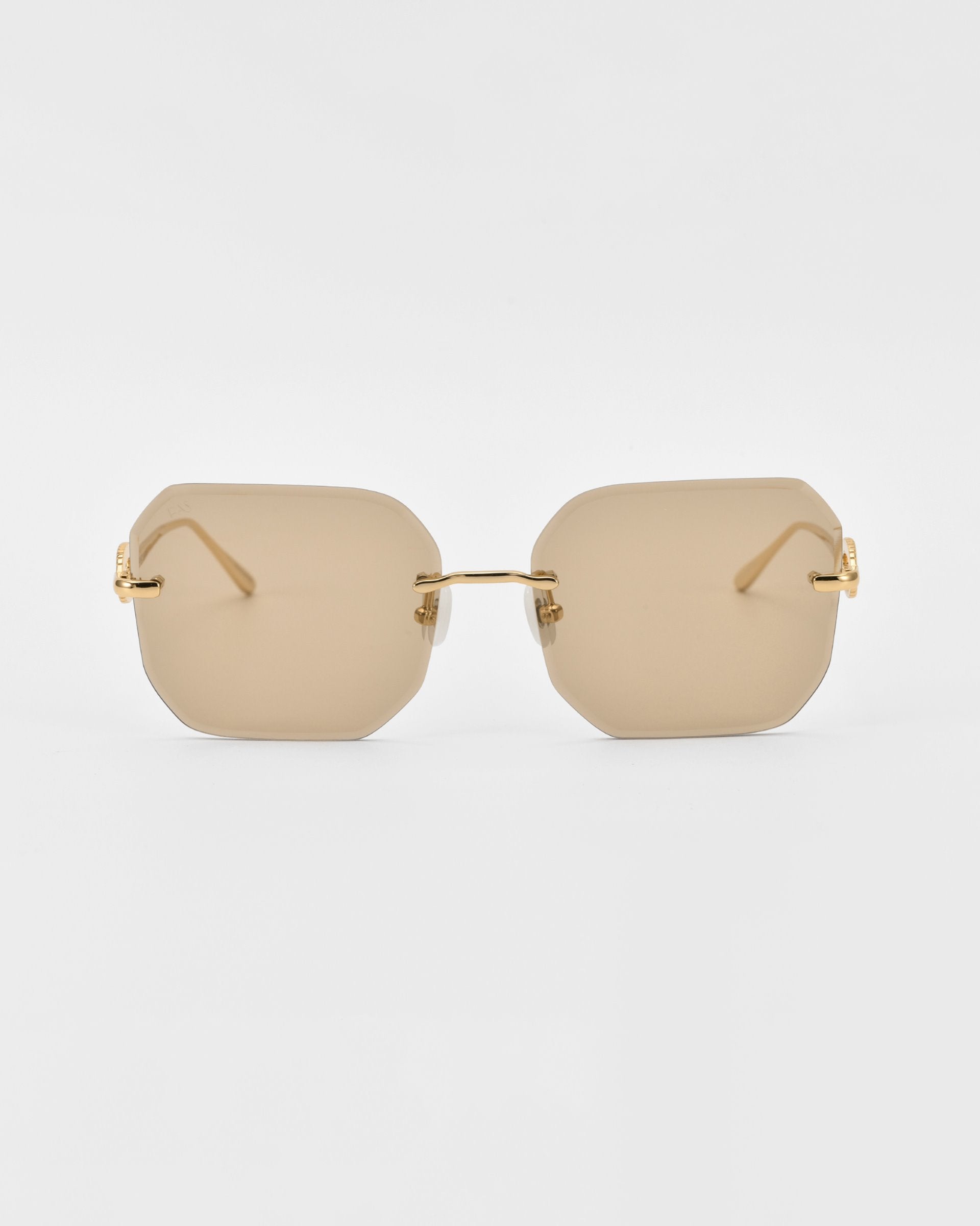 A pair of stylish For Art&#39;s Sake® Aria sunglasses featuring frameless, diamond-cut lenses with a rectangular, brown tint and gold metal arms. Jade-stone nose pads add a touch of elegance as they rest gently on the plain white background.
