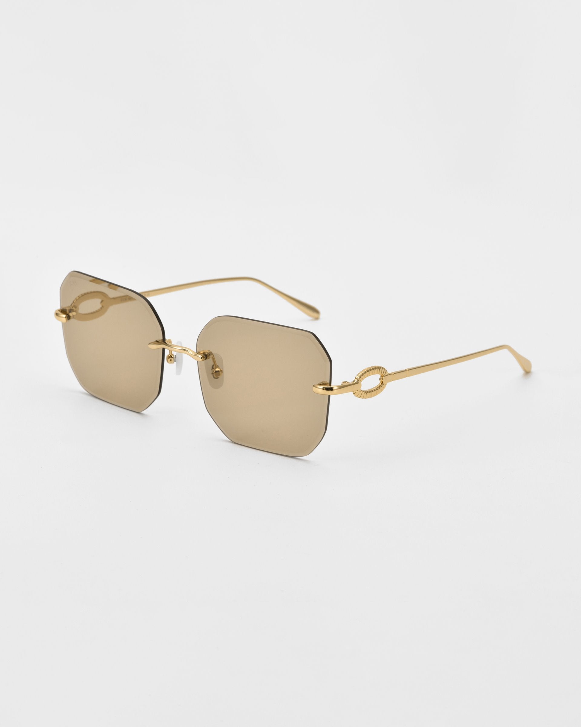 A pair of stylish For Art&#39;s Sake® Aria sunglasses with rimless, square diamond-cut lenses and gold-toned metal arms. The sunglasses feature a minimalist design with an elegant loop detail at the temple, adding a touch of luxury. The lenses have a light brown tint, complemented by jade-stone nose pads.