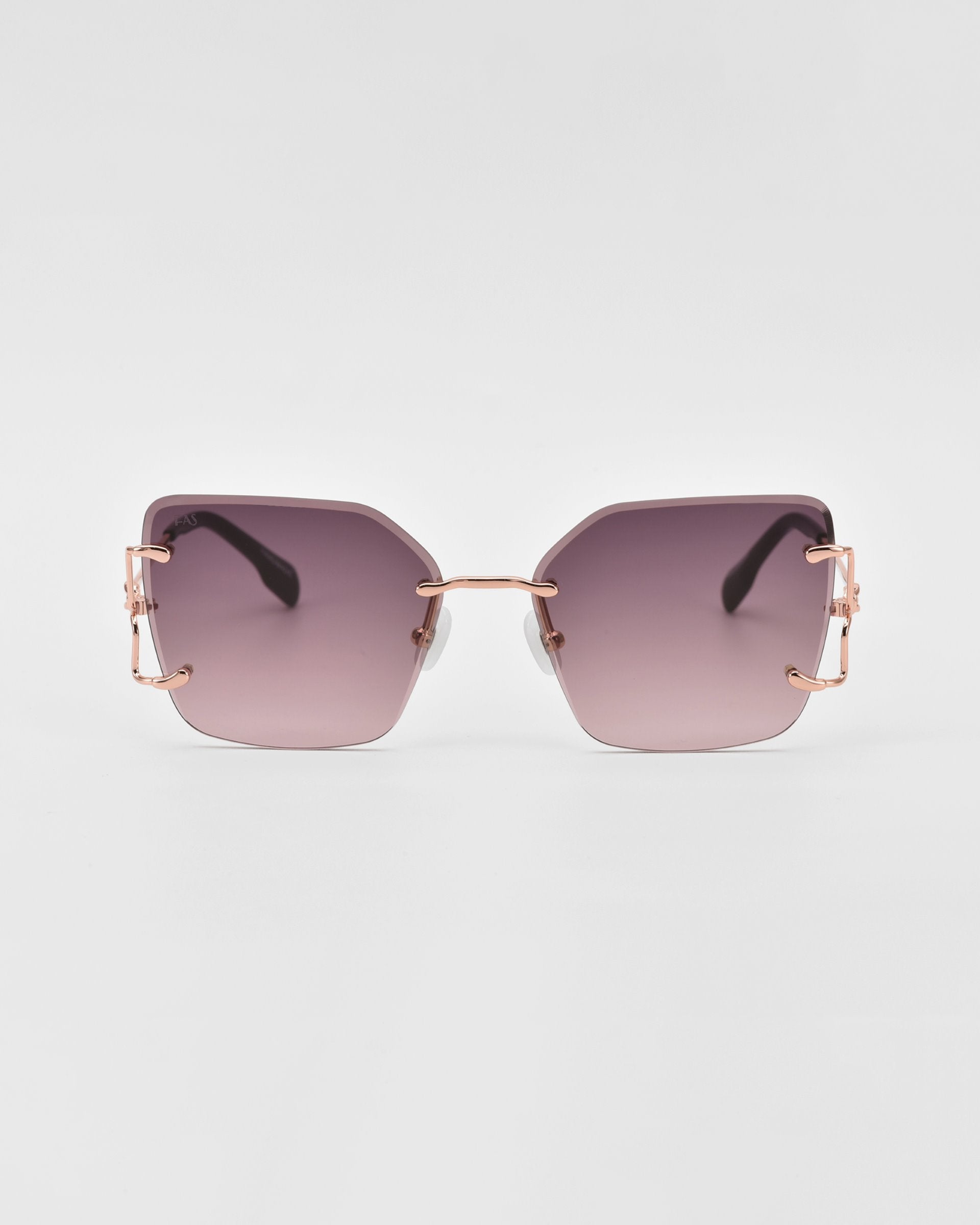 A pair of stylish For Art's Sake® sunglasses featuring rectangular purple-tinted lenses and rose gold frames. The design is sleek and modern with thin metal temples, adding a fashionable touch to the overall look. Enhanced with jade-stone nosepads for extra comfort, all set against a plain white background.