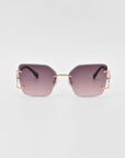 A pair of stylish For Art's Sake® sunglasses featuring rectangular purple-tinted lenses and rose gold frames. The design is sleek and modern with thin metal temples, adding a fashionable touch to the overall look. Enhanced with jade-stone nosepads for extra comfort, all set against a plain white background.