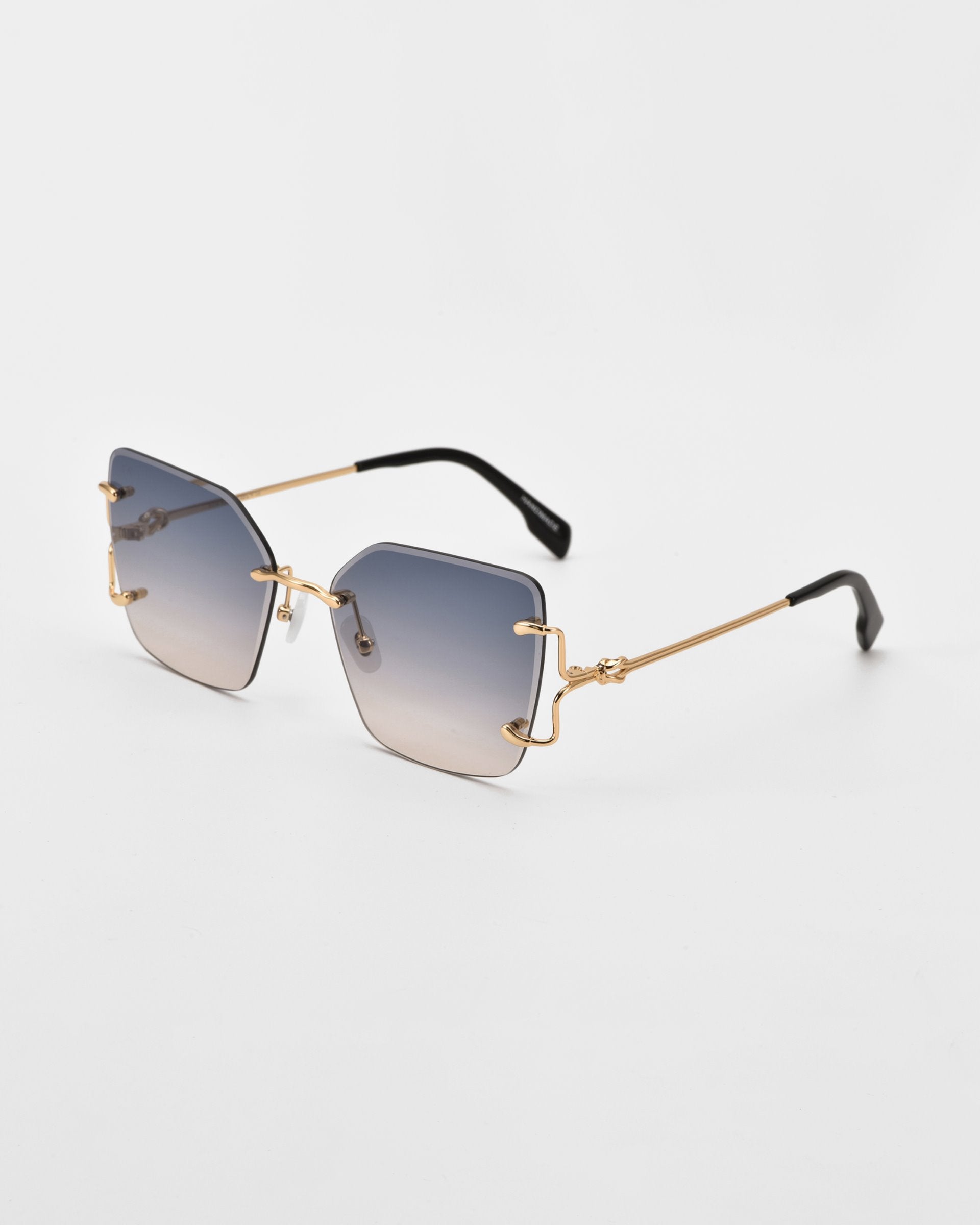 A pair of stylish For Art&#39;s Sake® Starlit sunglasses with gradient lenses transitioning from dark at the top to lighter at the bottom. They feature thin, gold-toned metal arms and uniquely shaped, rimless square frames. Jade-stone nosepads add a touch of elegance against the plain white background.