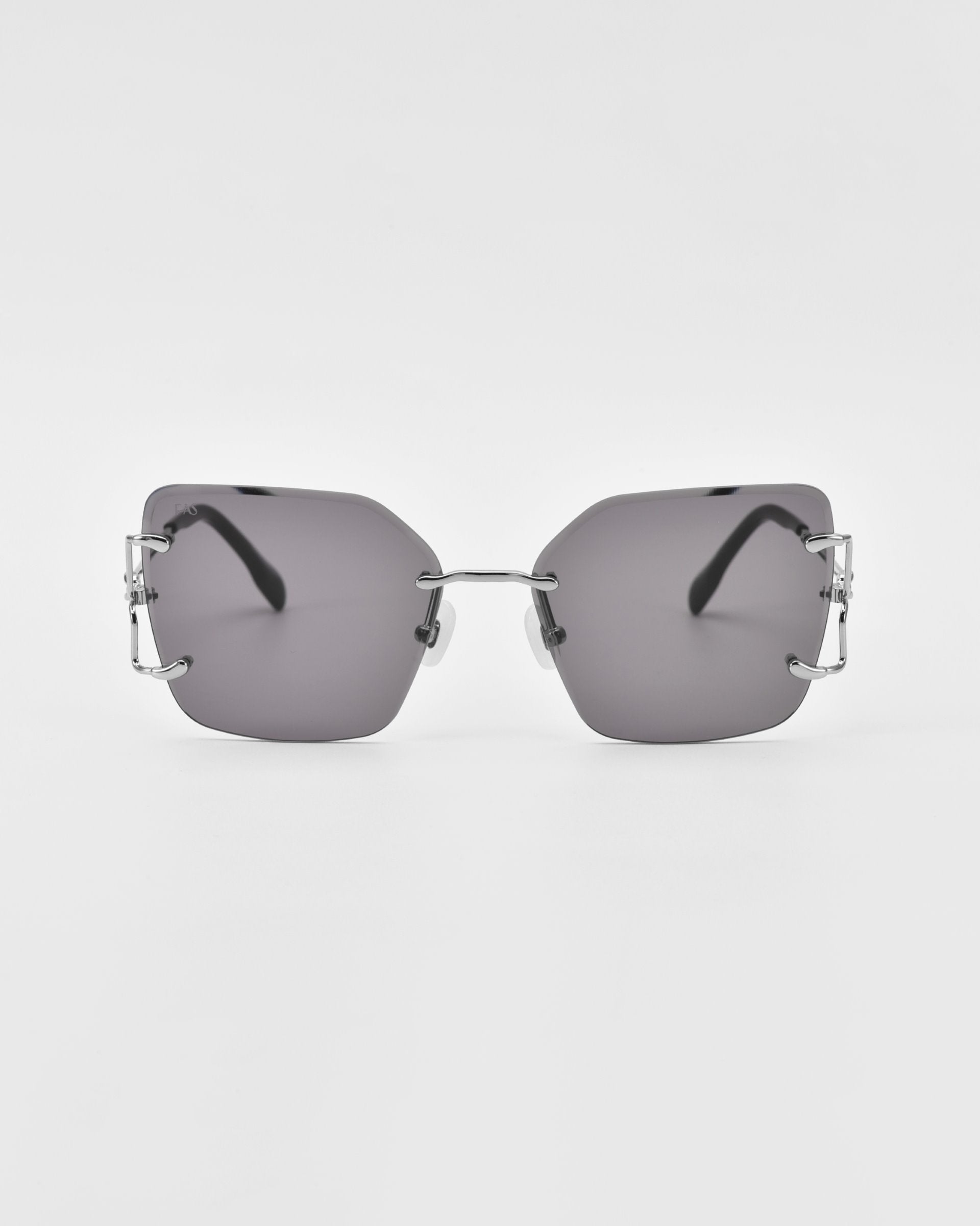 A pair of sleek, rectangular, rimless For Art&#39;s Sake® Starlit sunglasses with dark lenses and metallic bridge and temples. The minimalist design features thin, metallic ear rests, jade-stone nosepads, and exposed screw details at the lens corners on a plain white background.