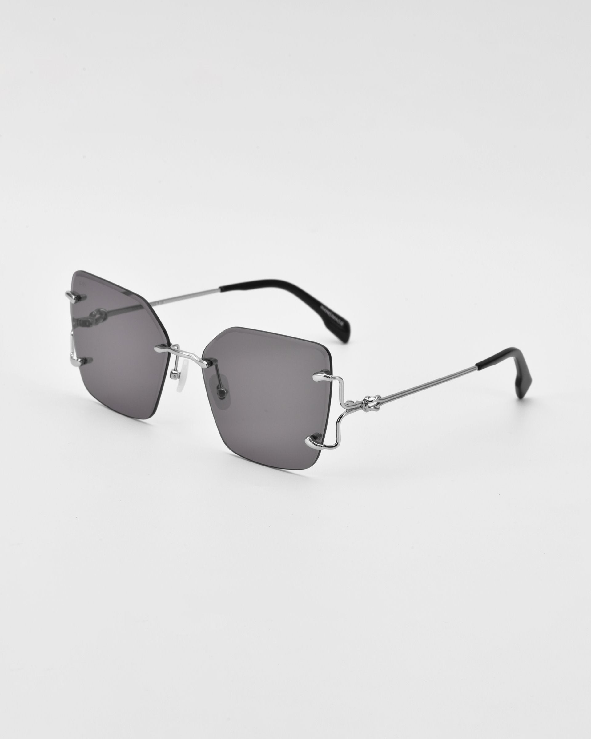 The For Art&#39;s Sake® Starlit sunglasses feature oversized square lenses and thin, metallic silver temples. The rimless design is complemented by jade-stone nosepads, adding a touch of luxury. The minimalist, sleek metallic nose bridge and hinges complete the look against a plain white background.