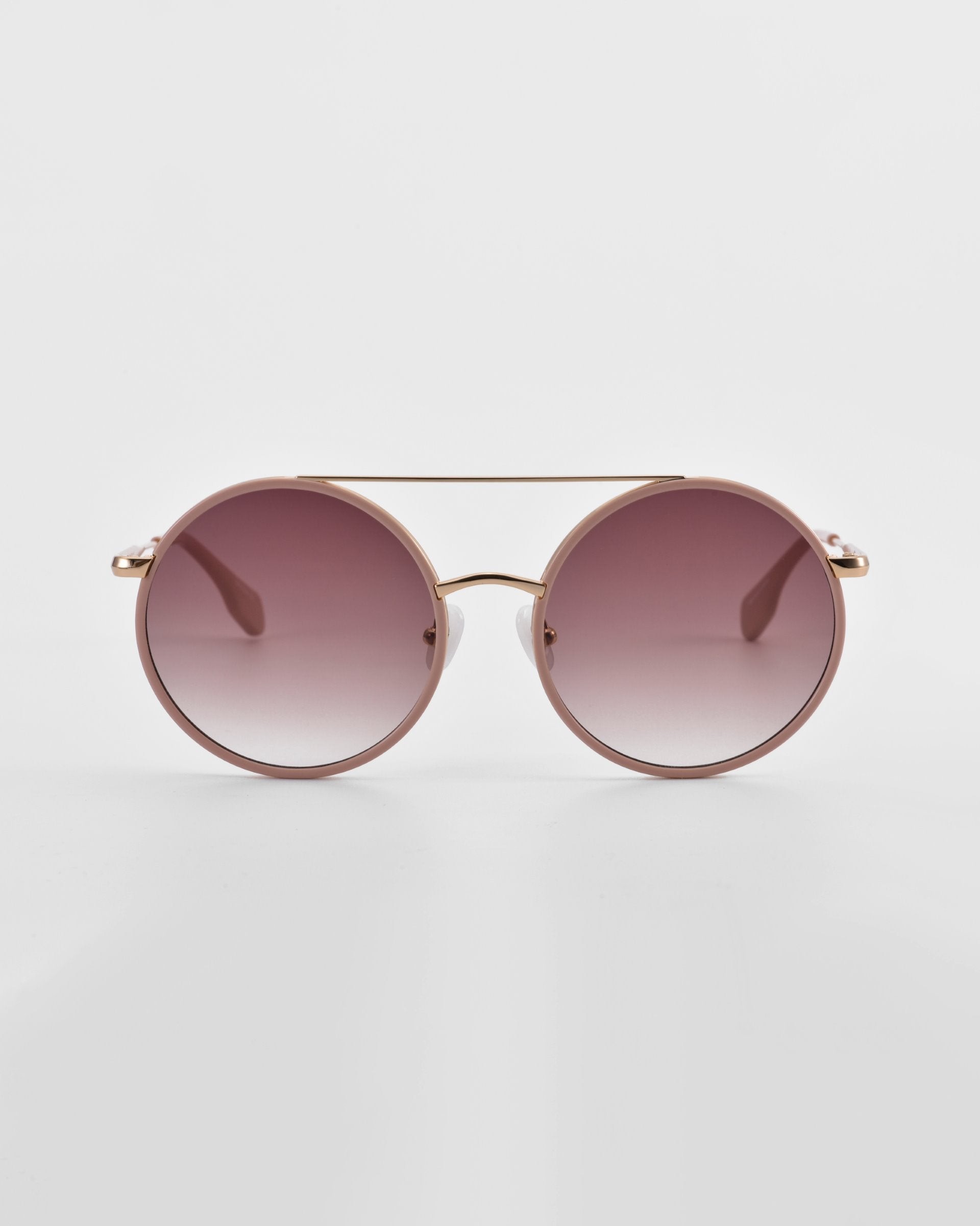 A pair of Orb by For Art&#39;s Sake® oversized round aviator sunglasses with dark tinted lenses and a thin, gold-colored frame. The Orb sunglasses, featuring elegant jade-stone nose pads, are positioned directly facing the camera on a white surface with a minimalist backdrop.