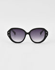 A pair of black oversized cat-eye Mirage sunglasses from For Art's Sake® with dark gradient lenses and silver accents on the temples. The frame, crafted from plant-based acetate, boasts a slightly geometric shape and is set against a plain white background.