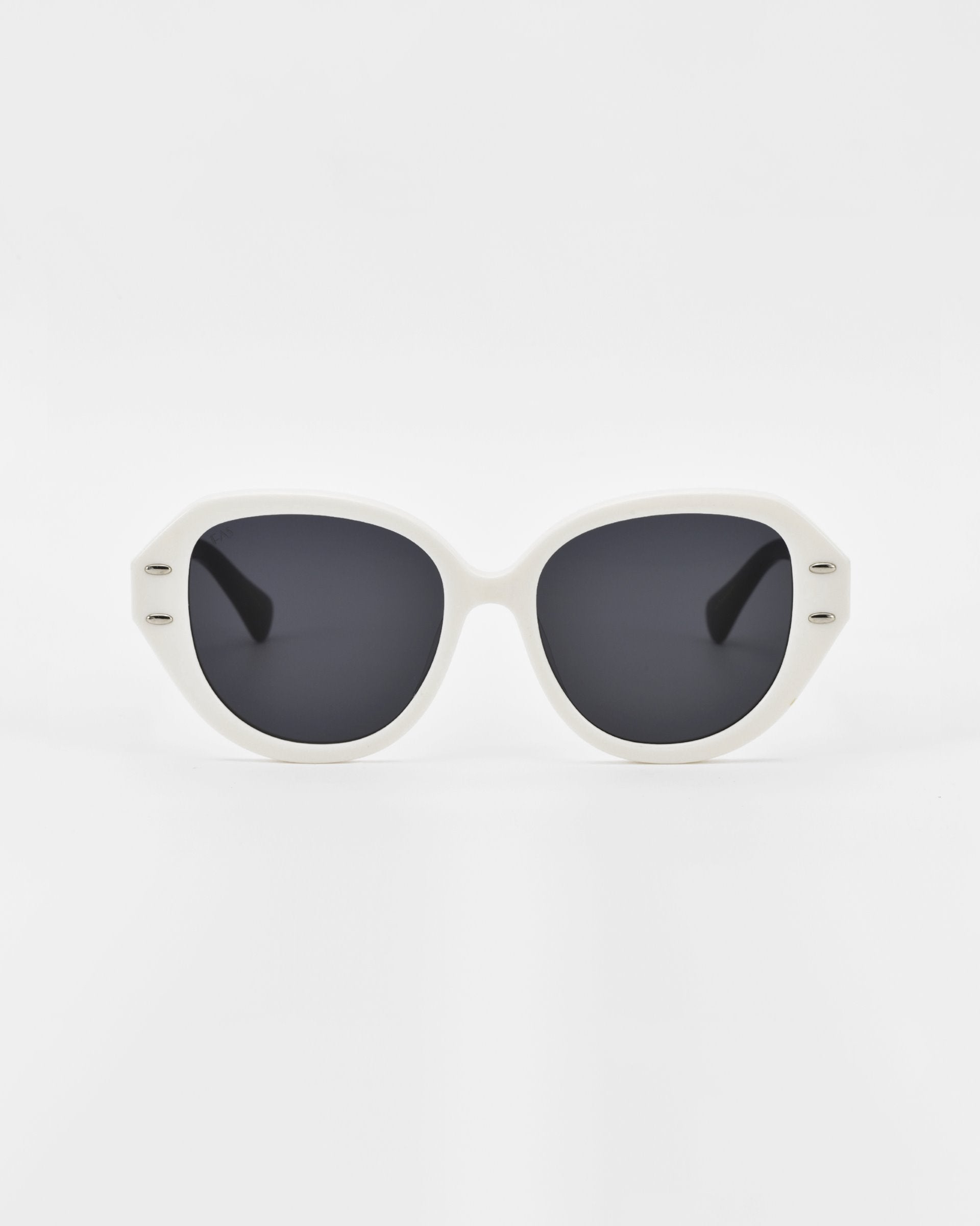 A pair of white-framed Mirage sunglasses by For Art&#39;s Sake® with black lenses, set against a plain white background. The design features rounded edges and a slightly retro style, crafted from plant-based acetate.