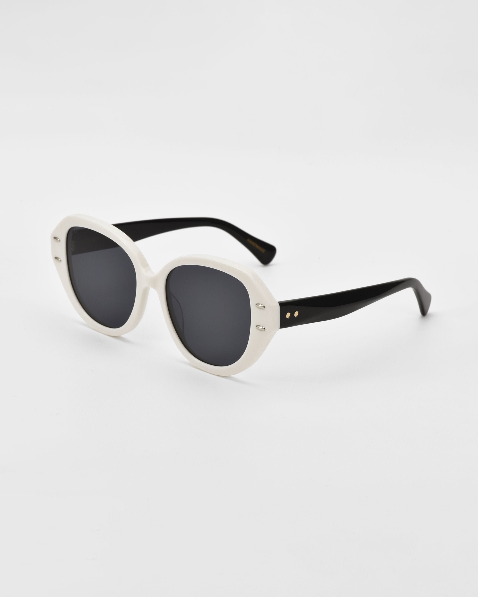 A pair of stylish cat-eye sunglasses with thick white, plant-based acetate frames and dark lenses. The temples are black, adding a contrasting touch to the design. The frames have a rounded, slightly oversized shape, giving them a modern and chic appearance. These are the Mirage sunglasses by For Art&#39;s Sake®.