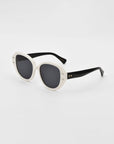 A pair of stylish cat-eye sunglasses with thick white, plant-based acetate frames and dark lenses. The temples are black, adding a contrasting touch to the design. The frames have a rounded, slightly oversized shape, giving them a modern and chic appearance. These are the Mirage sunglasses by For Art's Sake®.